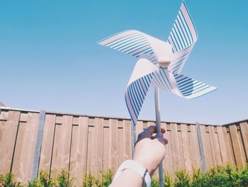 Person holding umbrella against clear blue sky