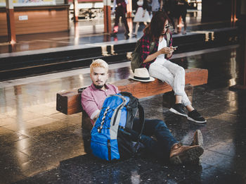 Full length of friends sitting at railroad station platform