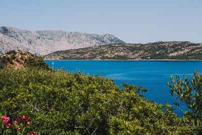 Scenic view of sea and mountains against clear blue sky