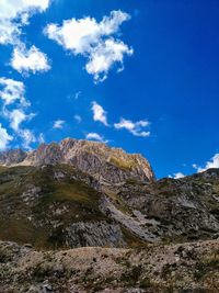 Low angle view of rocky mountain against blue sky