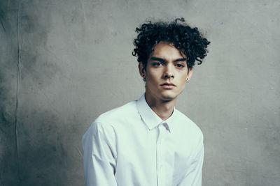 Portrait of young man standing against wall