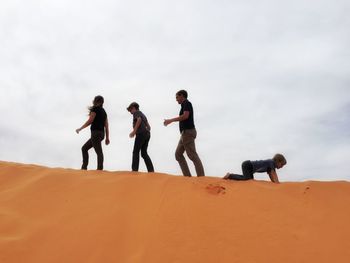 People on desert against cloudy sky