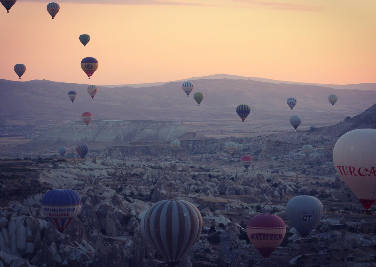 HOT AIR BALLOONS FLYING OVER LANDSCAPE DURING SUNSET