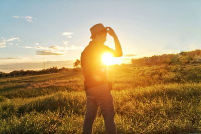 Silhouette man standing on field against sky during sunset