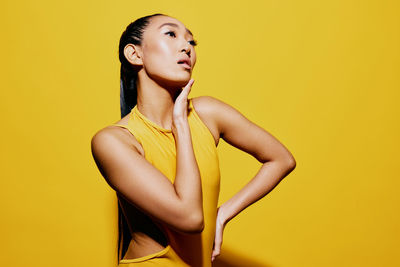 Portrait of young woman against yellow background