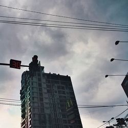 Low angle view of power lines against cloudy sky