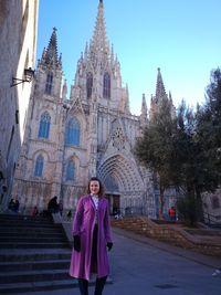 Portrait of young woman standing on road against cathedral