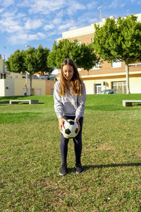 Full length of girl playing with soccer ball at lawn