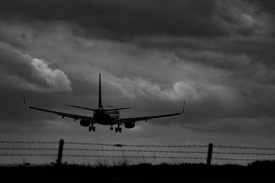 Low angle view of airplane flying against cloudy sky