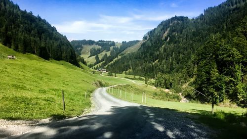 Road amidst trees and mountains against sky