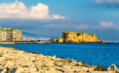 Buildings by sea against sky