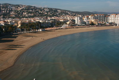 Scenic view of beach by town against sky