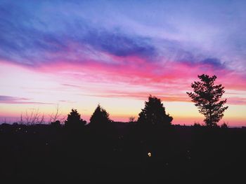 Silhouette trees against dramatic sky during sunset