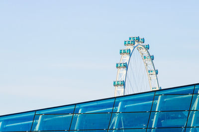 Low angle view of singapore flyer behind glass building