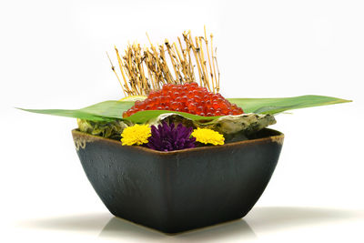 Close-up of fresh flowers in bowl against white background