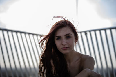 Portrait of woman against railing in city