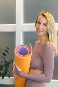 Portrait of beautiful young woman holding colorful mat for sports. sport and healthy 