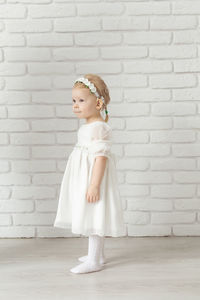 Portrait of cute girl standing against brick wall