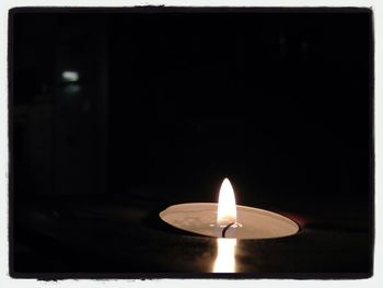 Lit candle in dark room