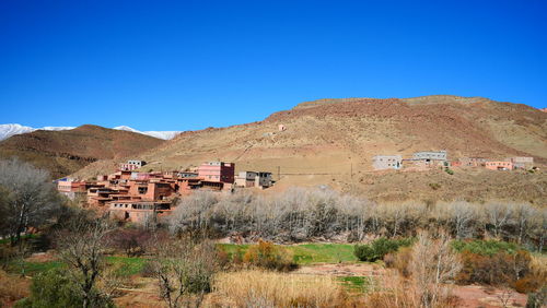 Scenic view of houses and mountains against clear blue sky