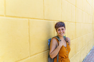 Young woman standing against wall