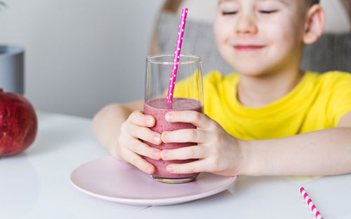 Boy holding drink in glass on table