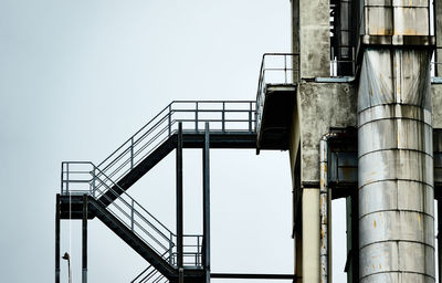  iron staircase next to an aluminium pipe at the tower of an industrial plant