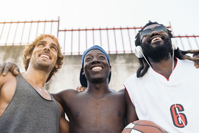 Low angle view of smiling friends looking away against wall