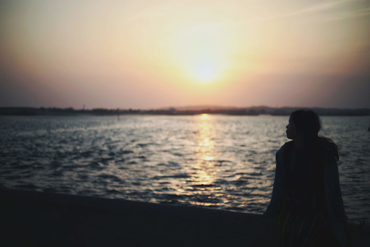 SILHOUETTE WOMAN STANDING AT BEACH DURING SUNSET