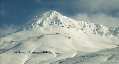 Scenic view of snowcapped mountains against cloudy sky