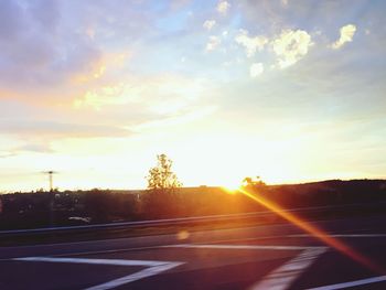 Empty road along countryside landscape at sunset