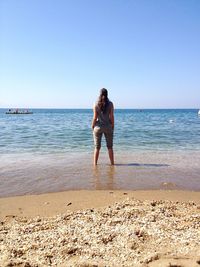 Full length of woman standing on beach against clear sky