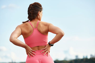 Woman looking away while standing against sky