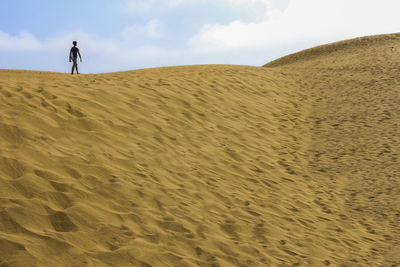 Teenage boy walking on sand at desert