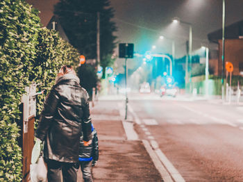 Rear view of man walking on street at night