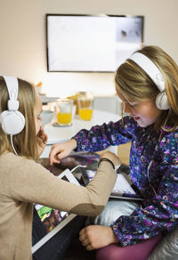 Sisters listening music on digital tablets in living room