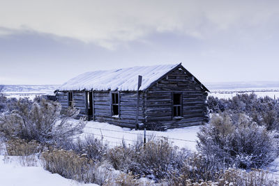 House on snow covered field against sky