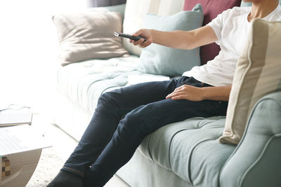 Midsection of man using mobile phone while sitting on sofa at home