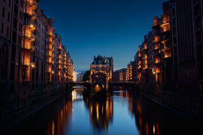 Reflection of illuminated buildings in city at dusk