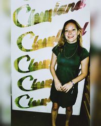 Portrait of a smiling young woman standing against wall