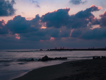 Scenic view of beach against sky at sunset