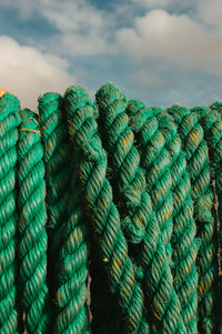 Green colored boat mooring rope against a blue sky with clouds