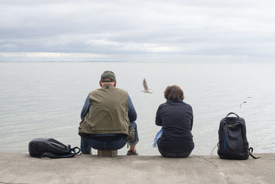 Rear view of people on beach against sky