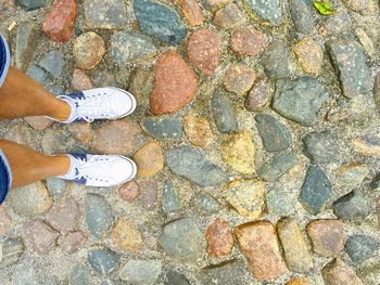 Low section of man standing on cobblestone footpath