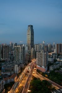 Aerial view of light trails on road amidst modern buildings against sky at night