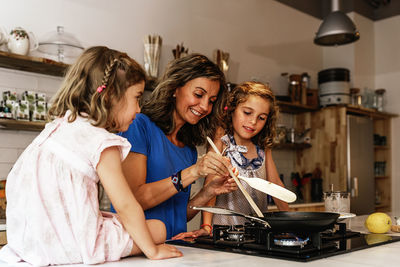 Mother and daughters preparing food in kitchen at home