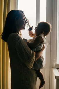 Side view of woman holding baby at home