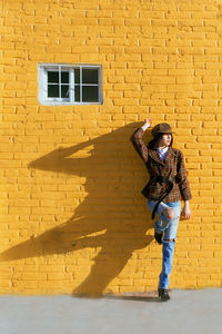 Full length of young woman standing against brick wall