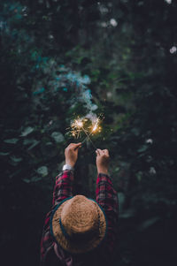 Rear view of woman holding sparklers in forest