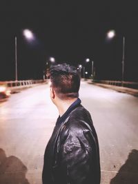 Rear view of man standing on street at night